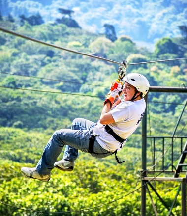 Zip-line rider above a forest canopy